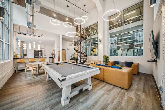 A room with a pool table and a spiral staircase.