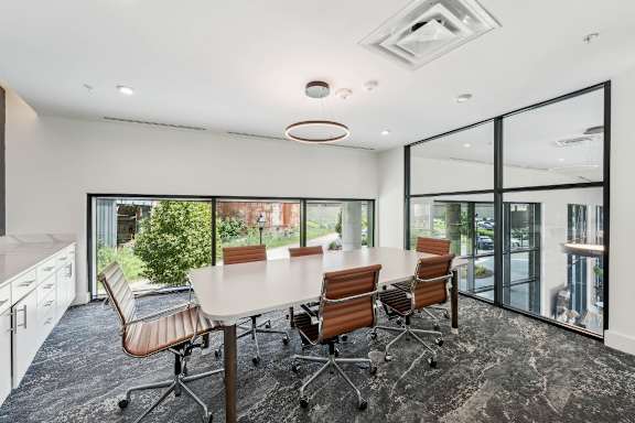 A conference room with a table and chairs and a glass wall.