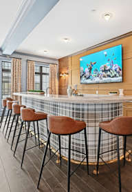 A bar area with a television on the wall and stools in front of it. at Maison Apartments, Apartments, Westerville, OH