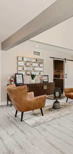 A modern living room with a large window and a kitchen area in the background.