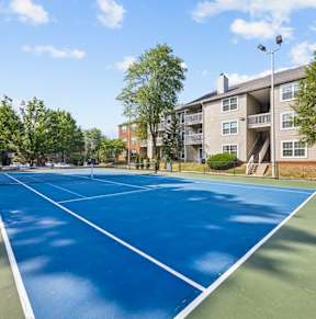 a tennis court with an apartment building in the background