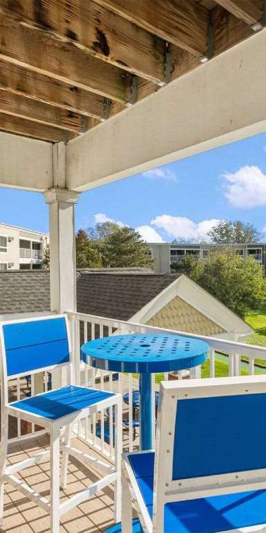 A patio with a table and chairs overlooking a pool.