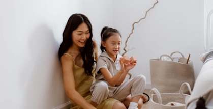 A woman and a child are sitting on the floor playing with a toy.