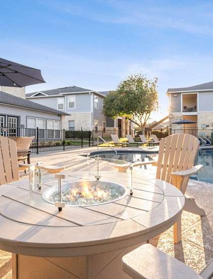 a patio with a table and chairs next to a swimming pool at Cypress Gardens, Cedar Park, TX