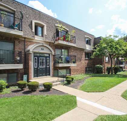 the view of a brick apartment building with a sidewalk and grass  at Village East, Franklin, Ohio