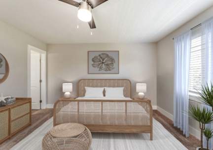A bedroom with a bed, a ceiling fan, and a side table. at The Courtyards of Chanticleer, Virginia Beach, VA