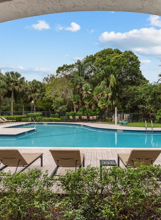 a swimming pool with chairs and a house in the background at Cypress Shores, Coconut Creek, 33063