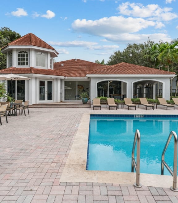a swimming pool with chairs and a house in the background at Cypress Shores, Coconut Creek, FL