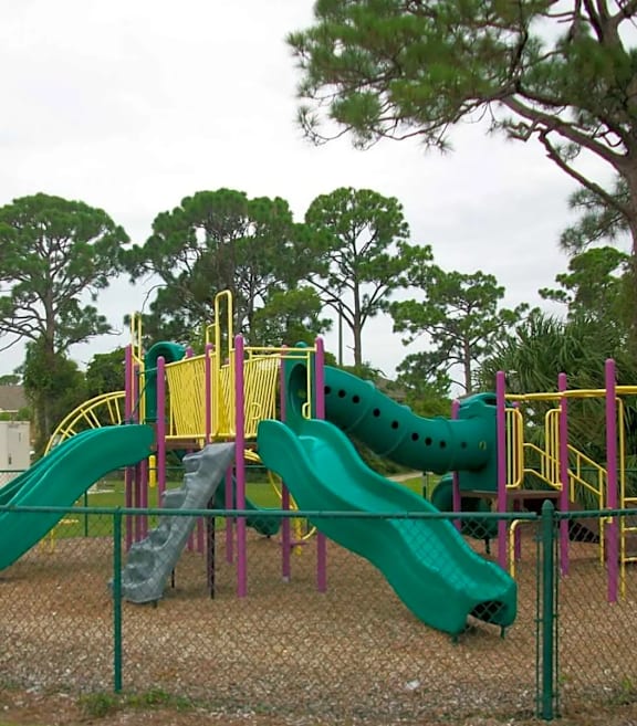 A playground with a green and yellow slide and a wooden structure.