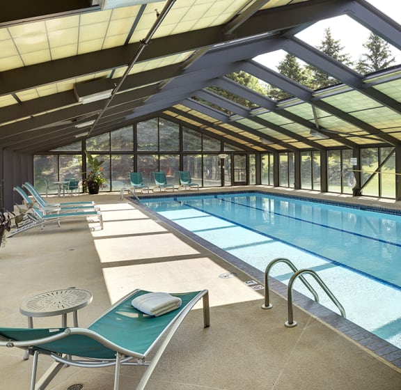 a swimming pool in a building with glass walls and a glass ceiling  at Regency Woods, Minnetonka, Minnesota