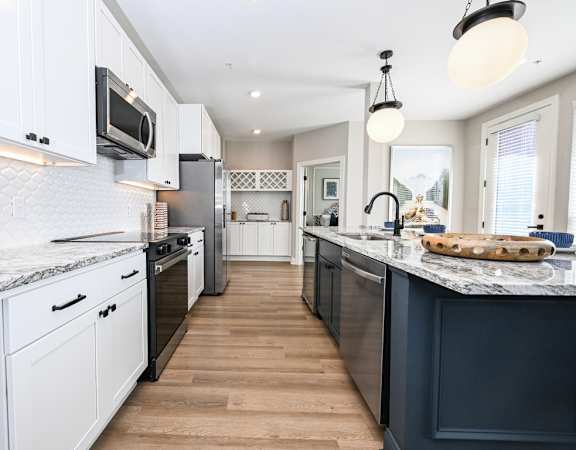 A kitchen with white cabinets and a marble countertop.