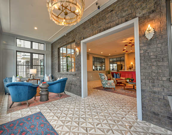 A room with a chandelier, a blue chair, and a patterned rug.