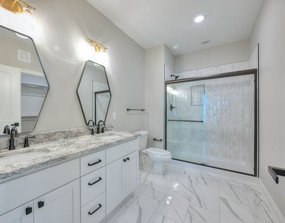 A bathroom with a marble countertop and a walk-in shower.