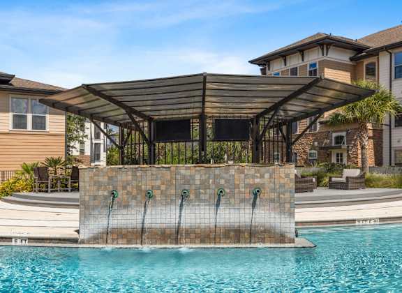 a pergola with a waterfall in front of a pool at The Loree Apartments, Jacksonville