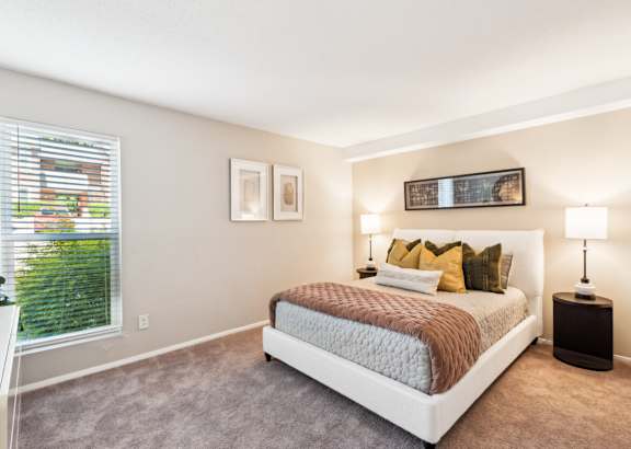 A bedroom with a large bed and a window with blinds. at Woodcreek Apartments, North Carolina