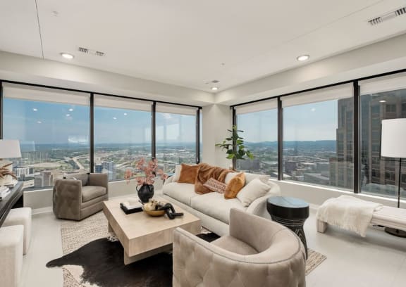 the living room has floor to ceiling windows and a view of the city