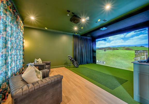 A room with a couch, a television, and a large screen showing a golf game.