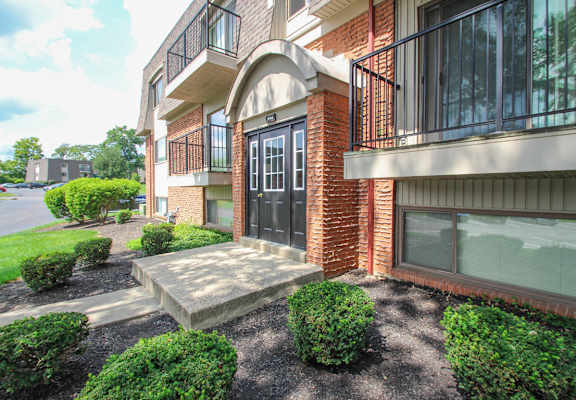 the entrance to a brick apartment building with a sidewalk and landscaping  at Village East, Franklin, Ohio