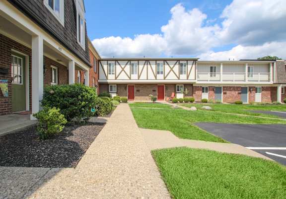a view of the exterior of an apartment building with a sidewalk and grass  at Village East, Franklin, Ohio