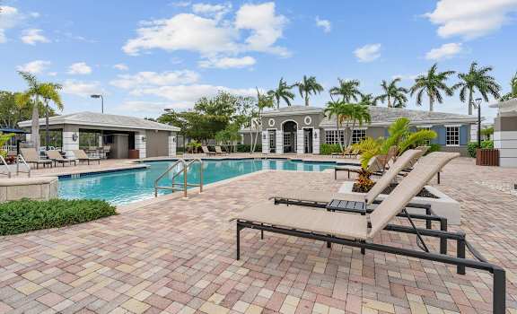 a swimming pool with lounge chairs and a house in the background at Promenade at Reflection Lakes, Florida
