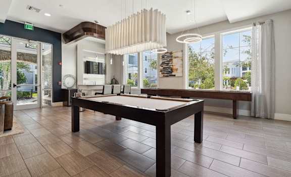 a pool table in a living room with a chandelier at Village at Terra Bella Apartments, Land O' Lakes, Florida