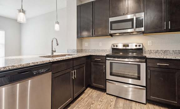 an empty kitchen with stainless steel appliances and marble counter tops at Village at Terra Bella Apartments, Land O' Lakes, Florida