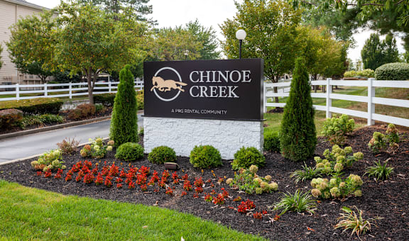 sign in front of a fence and flowers at Chinoe Creek Apartments in Lexington KY