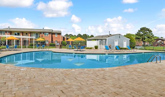 A large swimming pool surrounded by a brick patio.