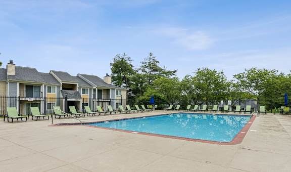 A swimming pool surrounded by lounge chairs and trees. at Chinoe Creek Apartments, Lexington, KY, 40502