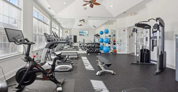 A gym with a variety of exercise equipment including treadmills, stationary bikes, and weight machines.