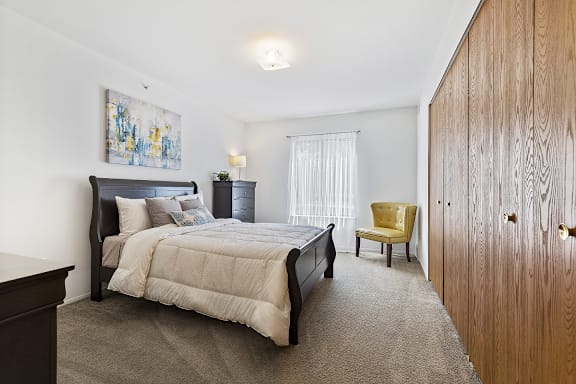 A bedroom with a bed, a chair, and a painting on the wall.