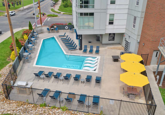 an aerial view of a resort style pool with lounge chairs and umbrellas