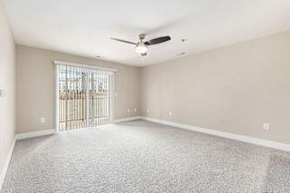 Spacious living room with ceiling fan and slider to balcony at Eagle Ridge Apartment Homes,  Michigan