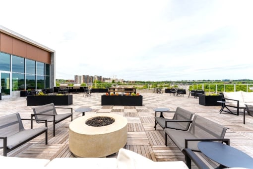 a rooftop patio with chairs and tables and a fire pit