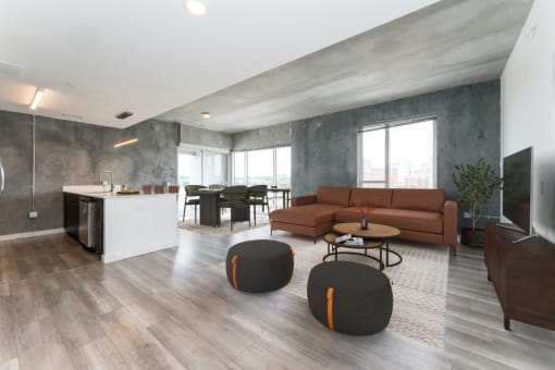 a living room and kitchen in an apartment with wood floors and concrete walls
