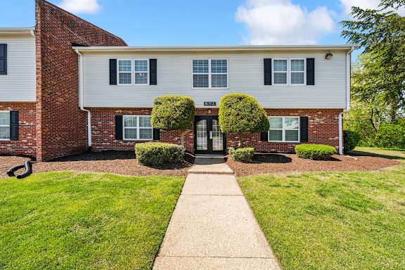 A white and brick building with a green lawn in front.