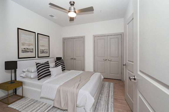 a white bedroom with a bed and a ceiling fan