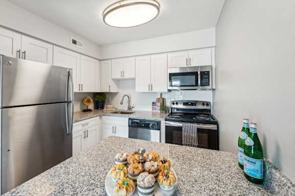 A kitchen with a granite countertop and stainless steel appliances.