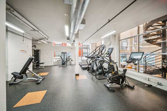 A gym with a variety of exercise equipment including treadmills, stationary bikes, and weight benches. at The Locks, Richmond, 23219