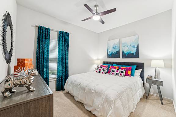 A bedroom with a white bed and a ceiling fan.