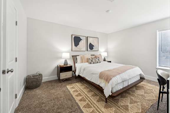 A bedroom with a bed, nightstands, and a rug.