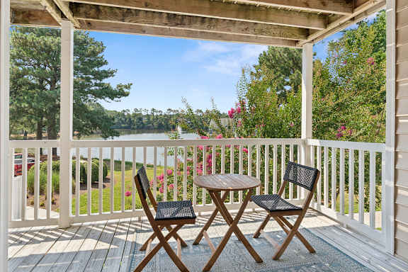A wooden table and two chairs are on a porch.