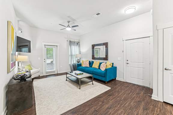 A living room with a blue couch and a ceiling fan.