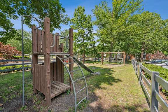 A playground with a wooden swing set and a metal slide.
