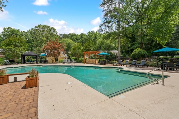 a swimming pool with trees in the background and a resort style pool