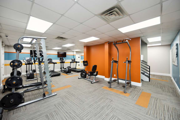 A gym with orange walls and a variety of equipment at River Oak Apartments, Louisville, KY, 40206