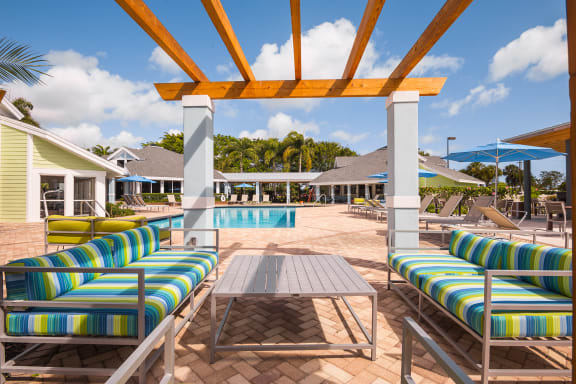 A patio with a pool and a wooden pergola at The Villages Apartment of Bayan Grove in Boynton Beach, FL