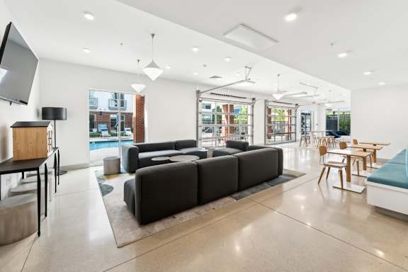 A modern living room with a black sofa and wooden chairs.