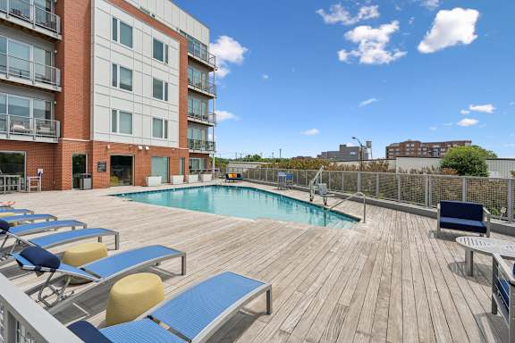 A wooden deck with a pool and sun loungers.