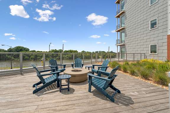 A wooden deck with blue chairs and a table.